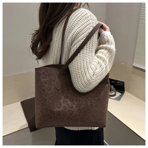 Grand sac cabas léopard marron foncé porté par un mannequin dans un décor chic