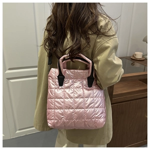 Detail of pink quilted puffer tote bag featuring black handles and detachable shoulder strap