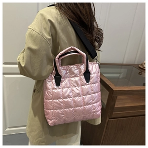Detailed view of pink quilted nylon tote bag with black strap worn by a model