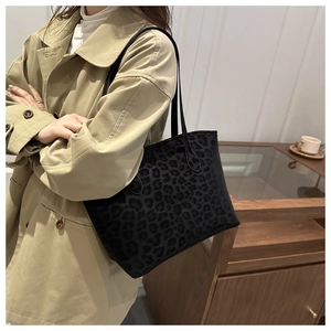 Détail du sac cabas léopard avec anses noires porté avec un trench-coat beige chic