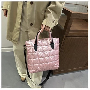 Detailed view of pink quilted nylon tote bag with black straps and puffy texture