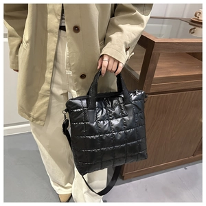 Detail of black quilted tote bag with glossy finish and detachable shoulder strap
