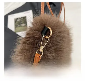 Macro detail of brown plush handbag featuring light gold metal hardware and leather strap