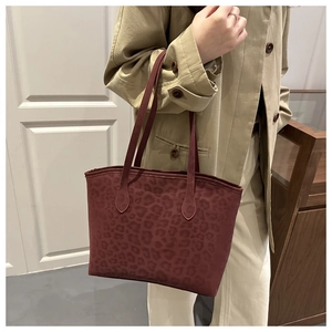 Détail macro du sac cabas en daim bordeaux avec motif léopard discret et bandoulière fine