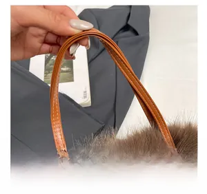Detail of the soft faux leather handle with white stitching on brown plush handbag