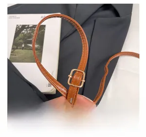 Detailed close-up of brown faux leather adjustable strap with golden metal buckle