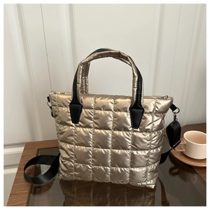 Detail of champagne gold quilted tote bag with black handles and metal hardware hooks