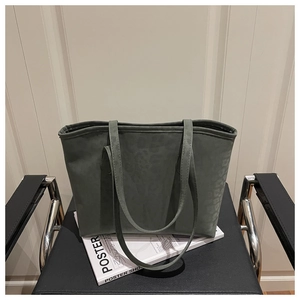 Détail d'un sac cabas vert foncé à imprimé léopard posé sur un magazine sur une chaise