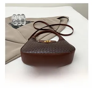 Detail view of woven texture and golden twist-lock on dark brown shoulder bag