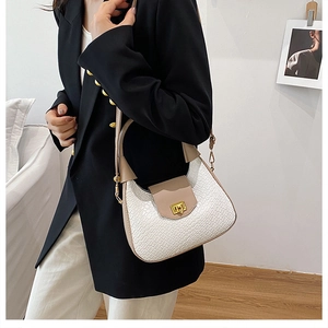 Detailed close-up of white woven leather shoulder bag with golden twist-lock closure