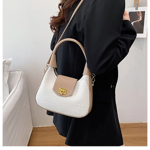 Detail of woven texture shoulder bag with gold twist lock on a minimalist crossbody model