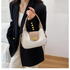 Close-up of a woven texture crescent shoulder bag with golden metallic twist lock detail
