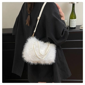 Detail of white faux fur crossbody bag against a black blazer for texture contrast