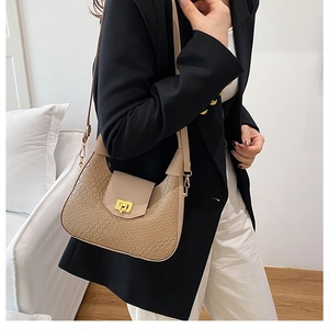 Detail of beige crocodile pattern texture and golden buckle on women's shoulder bag