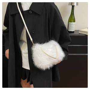Detail of white faux fur crossbody bag with soft texture and gold metal strap hardware