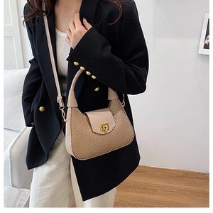 Close-up of beige woven texture crescent bag with gold twist lock and crocodile embossing