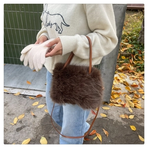 Close-up of brown plush faux fur handbag with leather strap on autumn background