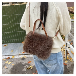 Rear view of a fluffy brown faux fur tote bag with leather straps on a park bench