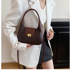 Detail of dark brown woven texture handbag with golden buckle and adjustable strap