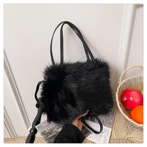 Detail of soft black faux fur handbag with dual leather handles and adjustable strap