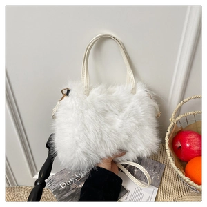 Detail of soft white faux fur handbag featuring leather handles and gold metal hardware