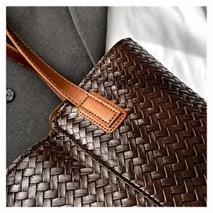 Macro shot of brown leather woven texture and detailed stitching on tote bag handle