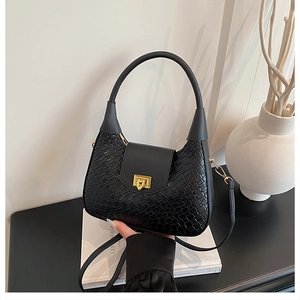 Detailed close-up of black woven texture leather bag with elegant gold metal buckle