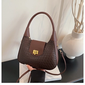 Detail of dark coffee woven leather texture and gold square buckle on a crescent bag