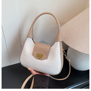 Close-up of woven texture, beige leather trim, and golden metal lock on the crescent bag