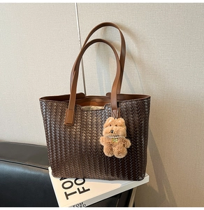 Detailed view of woven leather tote bag with dark coffee texture and plush puppy charm