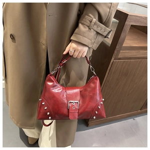Detail view of burgundy tote bag showing silver rivets and glossy wax leather texture