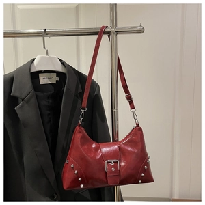 Detail of red vintage studded tote bag with silver buckle on a chrome clothes hanger