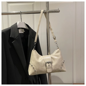 Close-up of beige rivet tote bag with metallic buckle and adjustable shoulder strap detail