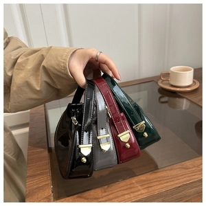 Close-up of four glossy crescent bags in black, gray, wine red and green with gold hardware
