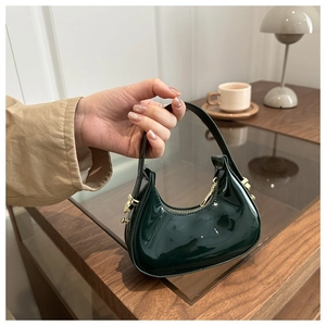 Close-up of a dark green patent leather crescent bag with sleek gold-tone metal zipper