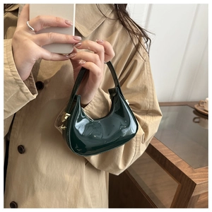 Detail of dark green patent leather crescent bag showing glossy texture and shoulder wear