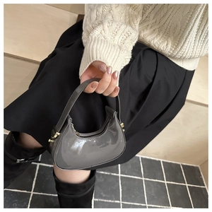 Detailed close-up of gray patent leather crescent bag with gold-tone hardware and zippers