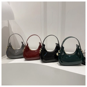 Macro detail of glossy patent leather crescent bags in multiple colors with gold hardware