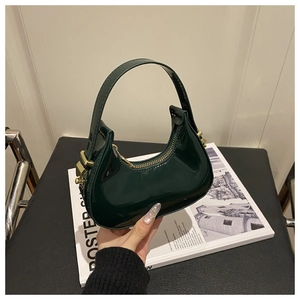 Detail of dark green crescent hobo bag with glossy finish and gold metal hardware