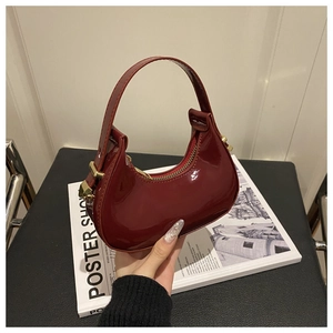 Detail of high-gloss burgundy crescent bag with premium gold zipper and leather texture