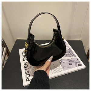 Detail of glossy black patent leather crescent bag with gold zipper and hardware