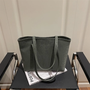 Sac fourre-tout vert foncé à motif léopard posé sur un fauteuil en cuir vintage