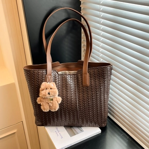 Deep brown woven leather tote bag with plush dog charm for daily office commute