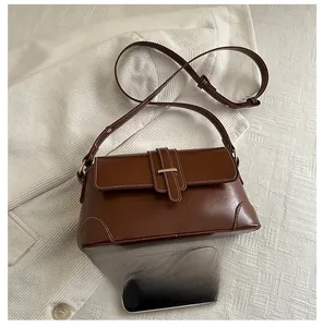 Detailed comparison of the vintage brown underarm bag size with a smartphone