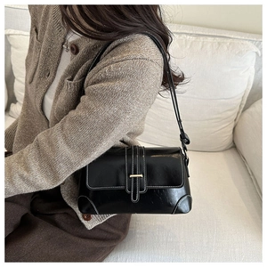 Detail of a vintage black underarm bag with contrast stitching and gold metal buckle