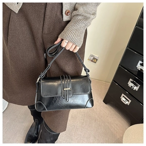 Close-up of vintage black PU leather handbag with gold buckle and contrast stitching details