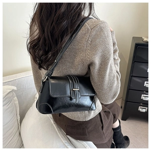 Detail of vintage black underarm bag with white contrast stitching and metallic buckle