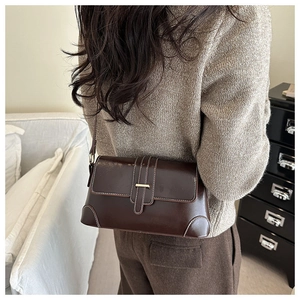 Detail shot of vintage dark brown leather shoulder bag with gold metal buckle