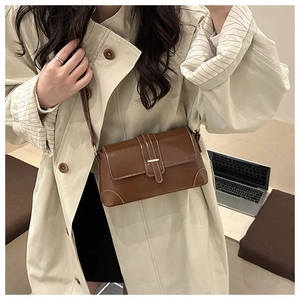 Detail of vintage brown patent leather shoulder bag with a gold buckle and adjustable strap