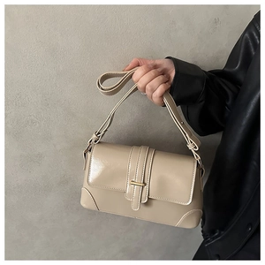 Detail of a beige vintage leather underarm bag with gold buckle and wide shoulder strap